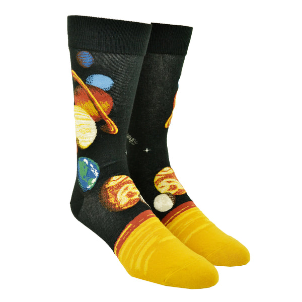 Shown on a foot form, a pair of Mod Socks’ black cotton men's crew socks with the entire planetary system in large detail