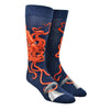 Shown on a foot form, a pair of Mod Socks’ dark blue cotton men's crew socks with large orange squid catching the tail of a gray whale