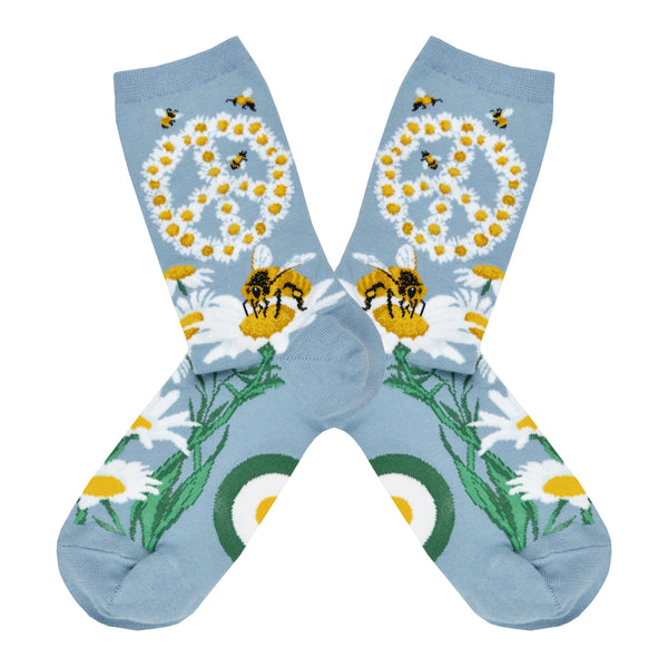 Shown in a flatlay, a pair of women's ModSocks cotton crew socks in light blue with a daisy peace sign on the leg and a daisy motif on the foot with bee's all over.