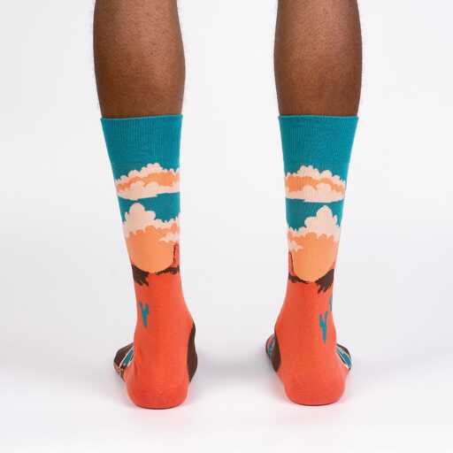 A pair of cotton crew length Sock it to Me socks featuring a scene from Monument Valley National Park on a persons feet, seen from behind.