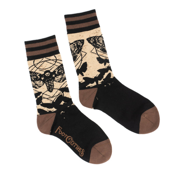 Shown in a flatlay, a pair of unisex crew socks in black and brown. The heel and toe are brown with a brown and black stripped cuff. The leg of these socks feature a deaths head moth. 