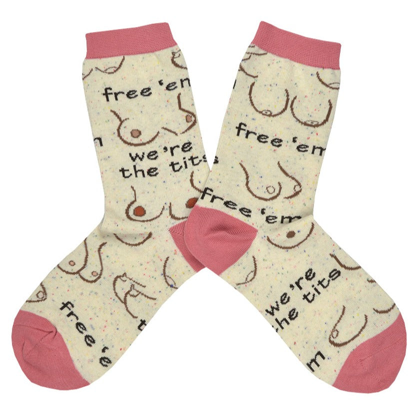 Shown in a flatlay, a pair of Oooh Yeah women's cotton crew socks in light tan with a pink heel, toe, and cuff. These socks feature various breast designs and shapes with the text 