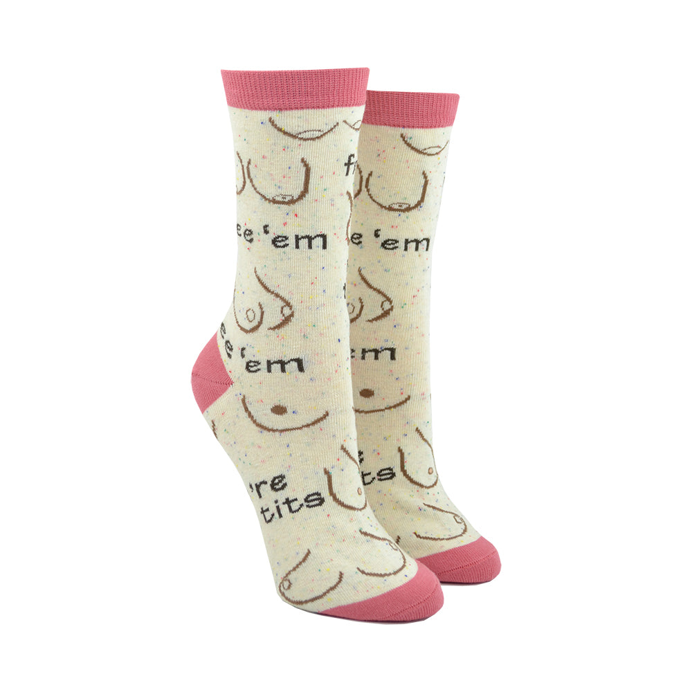 Shown on leg forms, a pair of Oooh Yeah women's cotton crew socks in light tan with a pink heel, toe, and cuff. These socks feature various breast designs and shapes with the text 