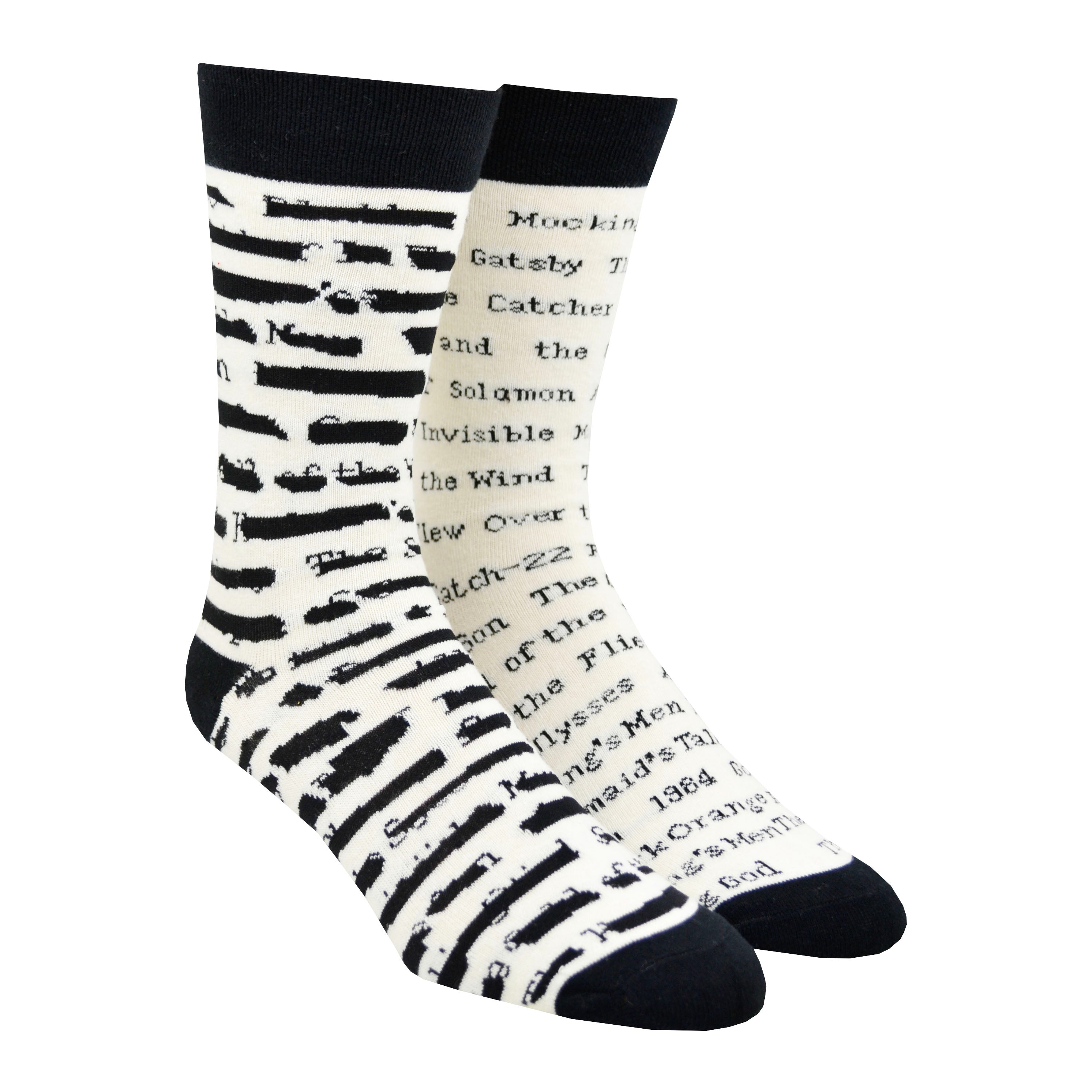 Shown on staggered leg forms, a pair of Out of Print brand unisex mismatched cotton crew socks in white with a black heel/cuff/toe. The right sock features typewriter font listings of titles of banned books. The left sock features the same titles but blacked out.