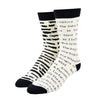 Shown on staggered leg forms, a pair of Out of Print brand unisex mismatched cotton crew socks in white with a black heel/cuff/toe. The right sock features typewriter font listings of titles of banned books. The left sock features the same titles but blacked out.