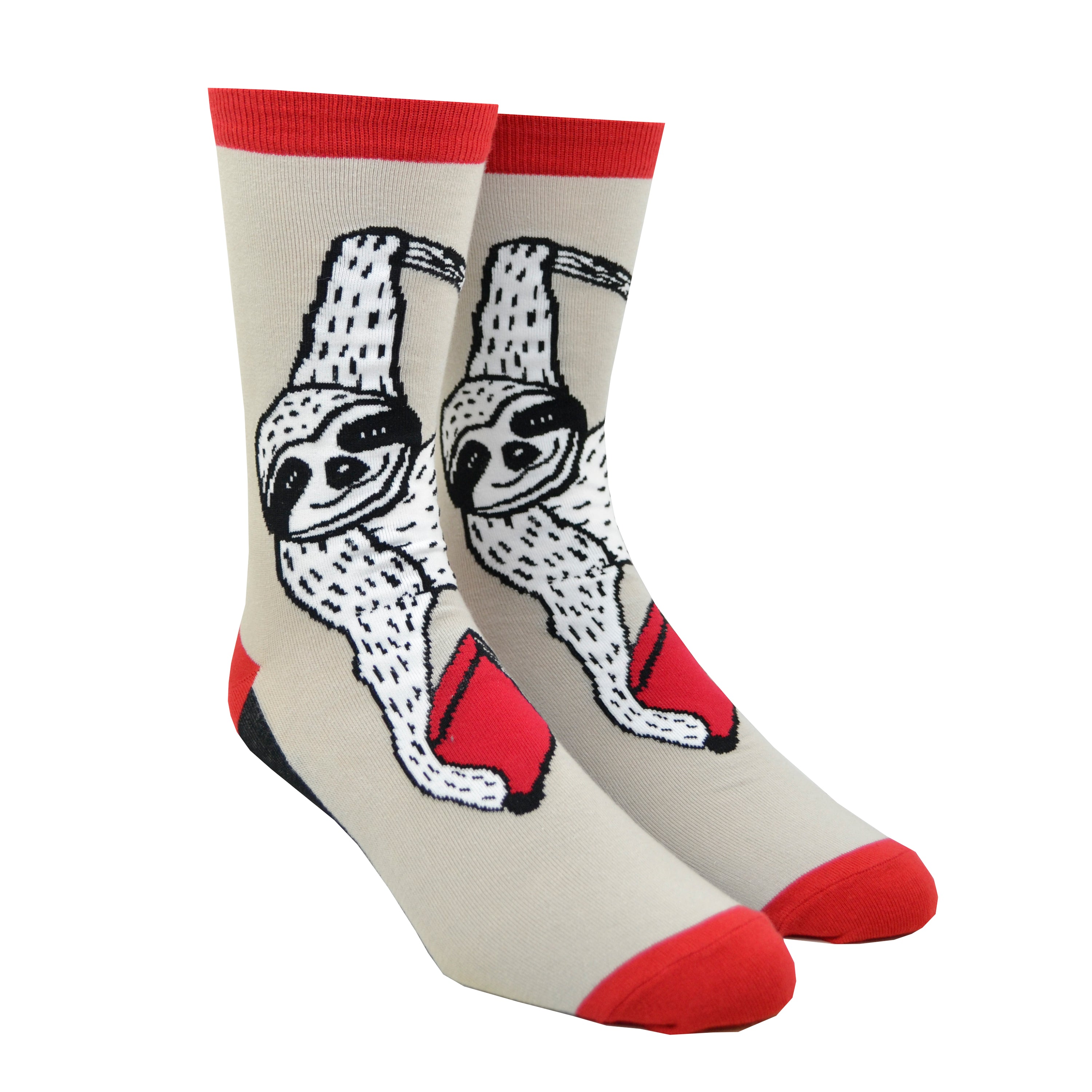 Shown in the larger size on leg forms, a pair of Out of Print brand unisex cotton crew socks in tan with a red heel/toe/cuff and a black sole. The sock features a black and white cartoon sloth hanging from a vine with a red book.