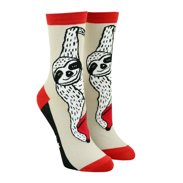 Shown in the smaller size on leg forms from the left , a pair of Out of Print brand unisex cotton crew socks in tan with a red heel/toe/cuff and a black sole. The sock features a black and white cartoon sloth hanging from a vine with a red book.