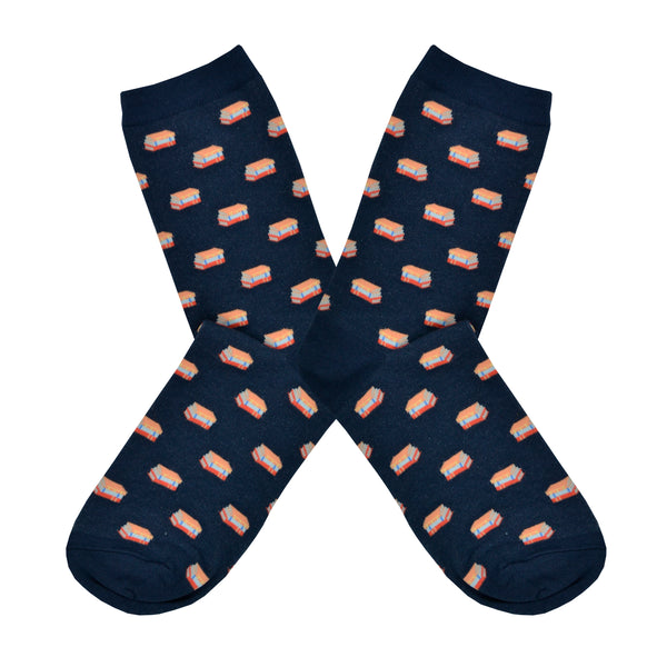 Shown in a flatlay, a pair of unisex Out of Print brand cotton crew sock in navy blue with an all over motif of little stacks of books.