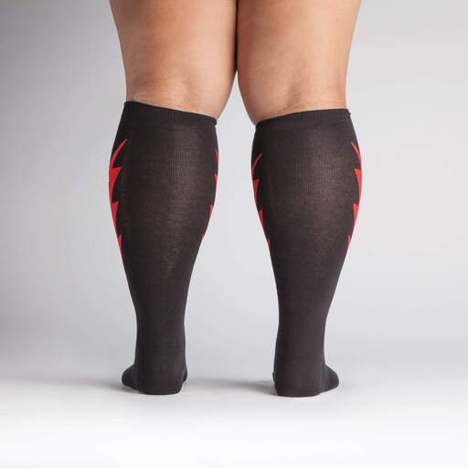 Shown on a tan model with thick calves from the back, a pair of Sock It To Me cotton knee high socks in black with a large red thunderbolt on each side.
