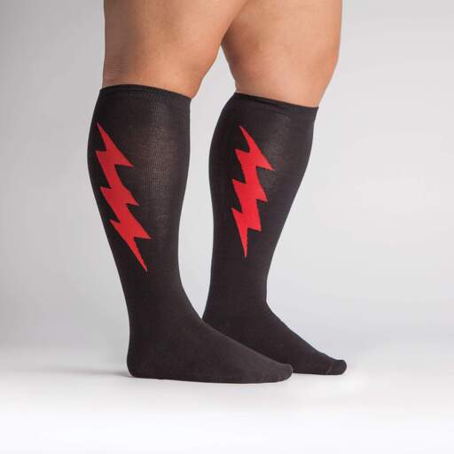 Shown on a tan model with thick calves from the side, a pair of Sock It To Me cotton knee high socks in black with a large red thunderbolt on each side.