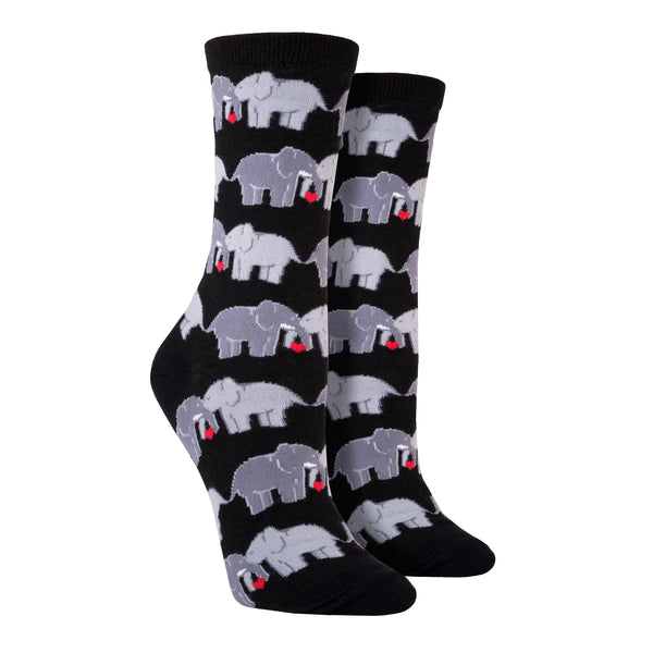 Shown on leg forms, a pair of women's Socksmith brand cotton crew socks in black with an all over design of 2 elephants linking trunks with a little red heart between them.