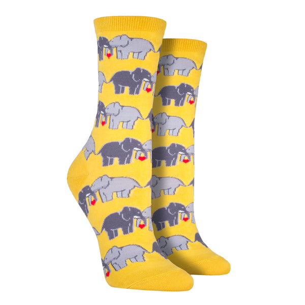 Shown on leg forms, a pair of women's Socksmith brand cotton crew socks in yellow with an all over design of 2 elephants linking trunks with a little red heart between them.