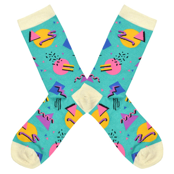 Shown in a flatlay, a pair of Socksmith brand women's bamboo crew socks in aqua with a cream heel, toe, and cuff. This sock features an all over design of 90's geometric shapes in bright colors.