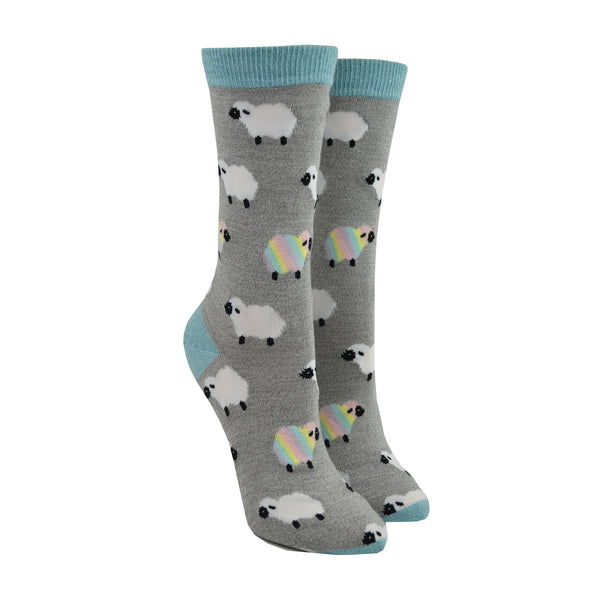 Shown on leg forms, a pair of Socksmith brand women's bamboo crew socks in grey with a light blue toe, heel, and cuff. This sock features an all over motif of white fluffy sheep with a few pastel rainbow sheep mixed in.