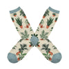 Shown in a flatlay, a pair of women's Socksmith brand cotton crew socks in ivory heather with a blue heather heel, toe, and cuff. This sock features an all over motif of various leafy potted plants.