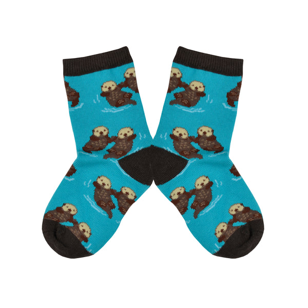 These blue cotton kid's crew socks with a brown heel, toe and cuff by the brand Socksmith feature adorable otters floating in the ocean holding hands.