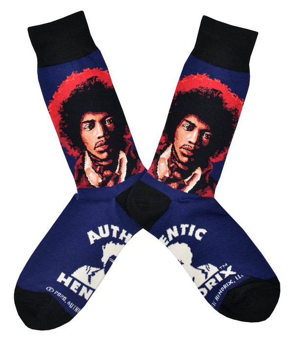 Shown in a flatlay, a pair of Socksmith's blue cotton men's crew socks with black cuff/heel/toe, and Jimi Hendrix portrait