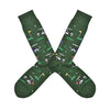 Shown in a flatlay, a pair of Socksmith's dark green cotton men's crew socks with golf hole markers and golf carts in an all-over pattern