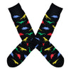 Shown in a flatlay, a pair of Socksmith's black cotton men's crew socks with multicolor dinosaur shape pattern