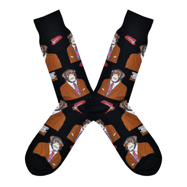 Shown in a flatlay, a pair of Socksmith men's black cotton crew socks with black cuff/heel/toe featuring an all over design of a monkey in a suit and tie.