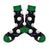 Shown in a flatlay, a pair of Socksmith's black cotton men's crew socks with dark green cuff/heel/toe and all-over pattern of golf balls and tees