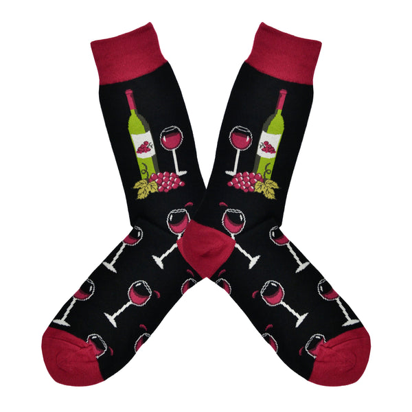 Shown in a flatlay, a pair of Socksmith men's cotton crew sock in black with a dark red cuff, heel, and toe. On the leg of the socks is a green wine bottle, a glass of red wine and some grapes. The full wine glasses continue down the foot of the sock.
