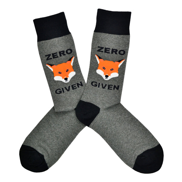Shown in a flatlay, a pair of Socksmith brand men's cotton crew socks in grey with black heel/cuff/toe and a cartoon fox face on the leg. The text on the sock reads, "Zero (fox) Given" using the fox design in between the words.