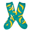 Shown in a flatlay, a pair of Socksmith's teal-green cotton women’s crew socks with ripe green banana fruit pattern