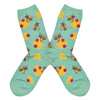 Shown in a flatlay, a pair of Socksmith’s light green cotton women’s crew socks with bee print including yellow honeycombs