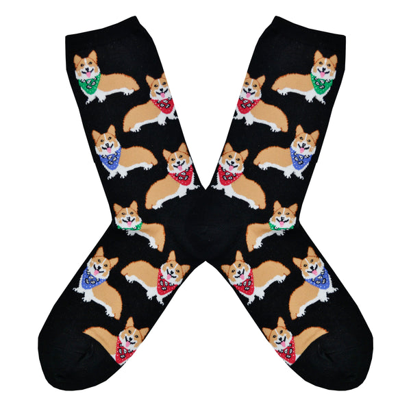 Shown in a flatlay, a pair of Sock Smith brand women's cotton crew socks in black featuring an all over motif of blonde corgis in blue, red, and green bandanas.