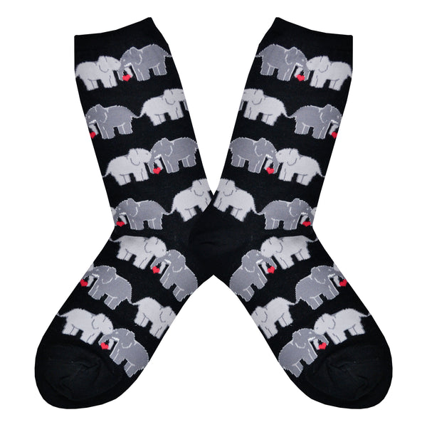 Shown in a flatlay, a pair of women's Socksmith brand cotton crew socks in black with an all over design of 2 elephants linking trunks with a little red heart between them.