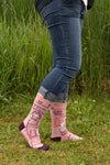 Shown on a model standing in a grassy field. They are wearing blue jeans and the "Go Away I'm Introverting" socks. 