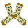 Shown in a flatlay, a pair of Socksmith brand women's bamboo crew socks in cream with a gold toe, heel, and cuff. This sock features different types of cactus plants in shades of green all over the sock.