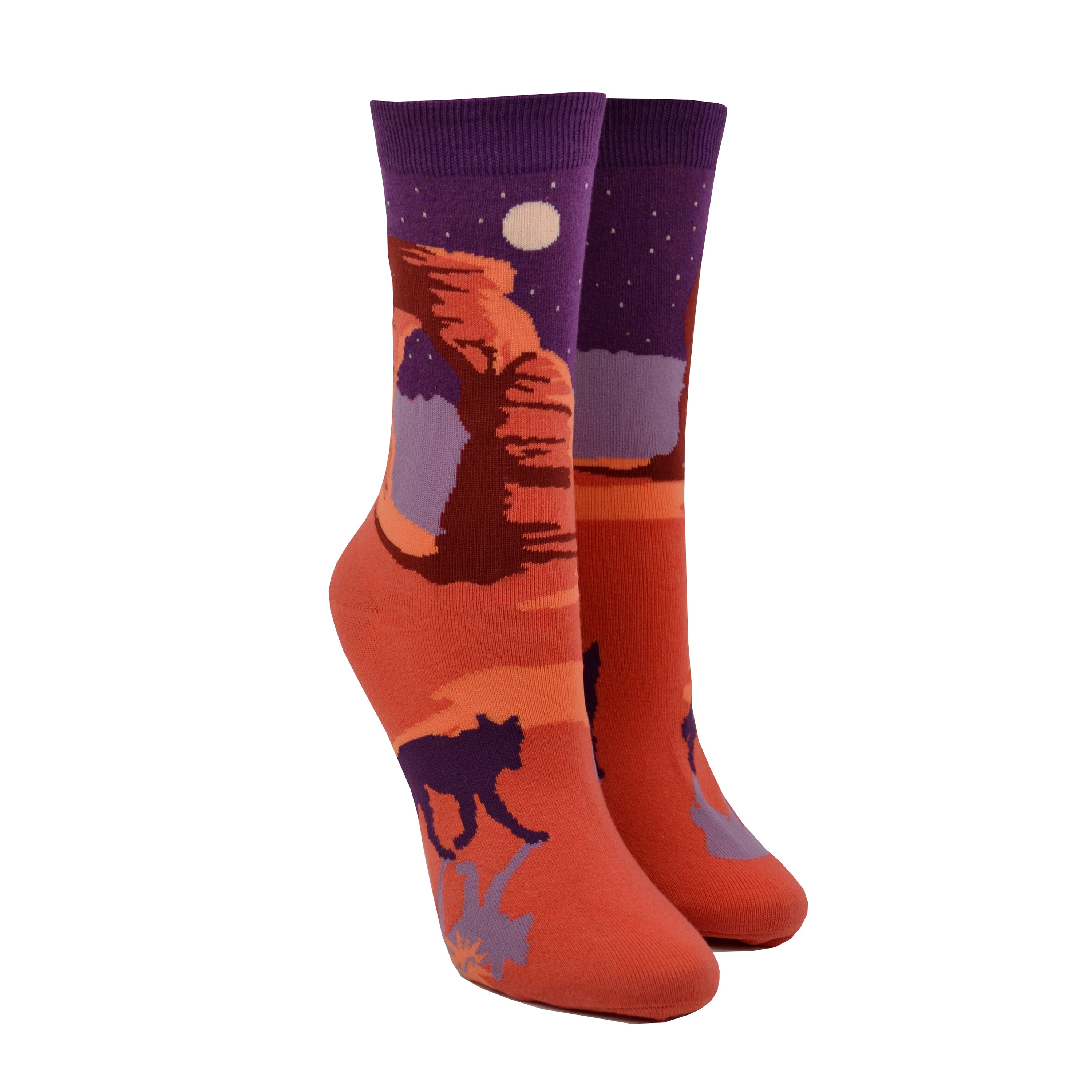 Shown on leg forms, a pair of Sock It to Me brand women's cotton crew socks with an orange heel/toe an a purple cuff. These socks feature an arch from Arches National Park on the leg and a coyote on the foot of the sock as well as the words 