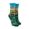 Shown on foot forms, a pair of women's Sock it to Me cotton crew socks with the Yellowstone National Park Grand Prismatic Spring depicted on the sock. The leg features the spring with a blue sky background while the foot is dark green with light green bear silhouettes.