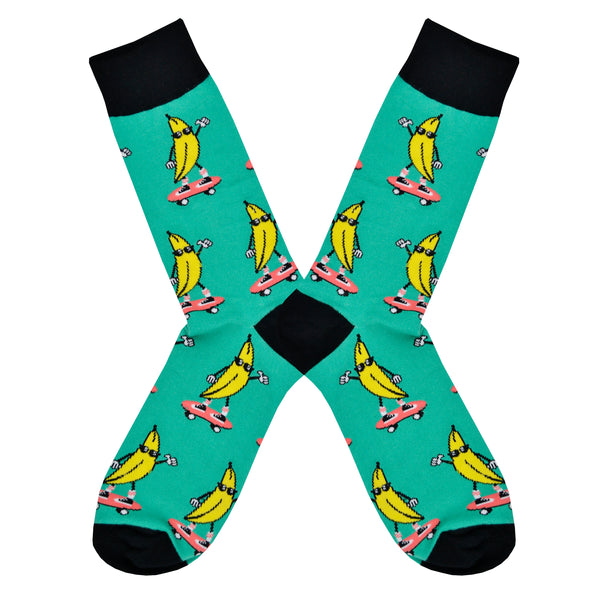 Shown in a flatlay, a pair of Sock It To Me turquoise cotton men's crew socks with black cuff/heel/toe and goofy bananas skateboarding while wearing cool sunglasses