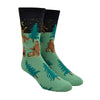 Shown on a foot form, a pair of Sock It To Me green cotton men's crew socks with black starry sky and various sasquatches enjoying a campfire (playing banjo, roasting marshmallows) among a pine forest