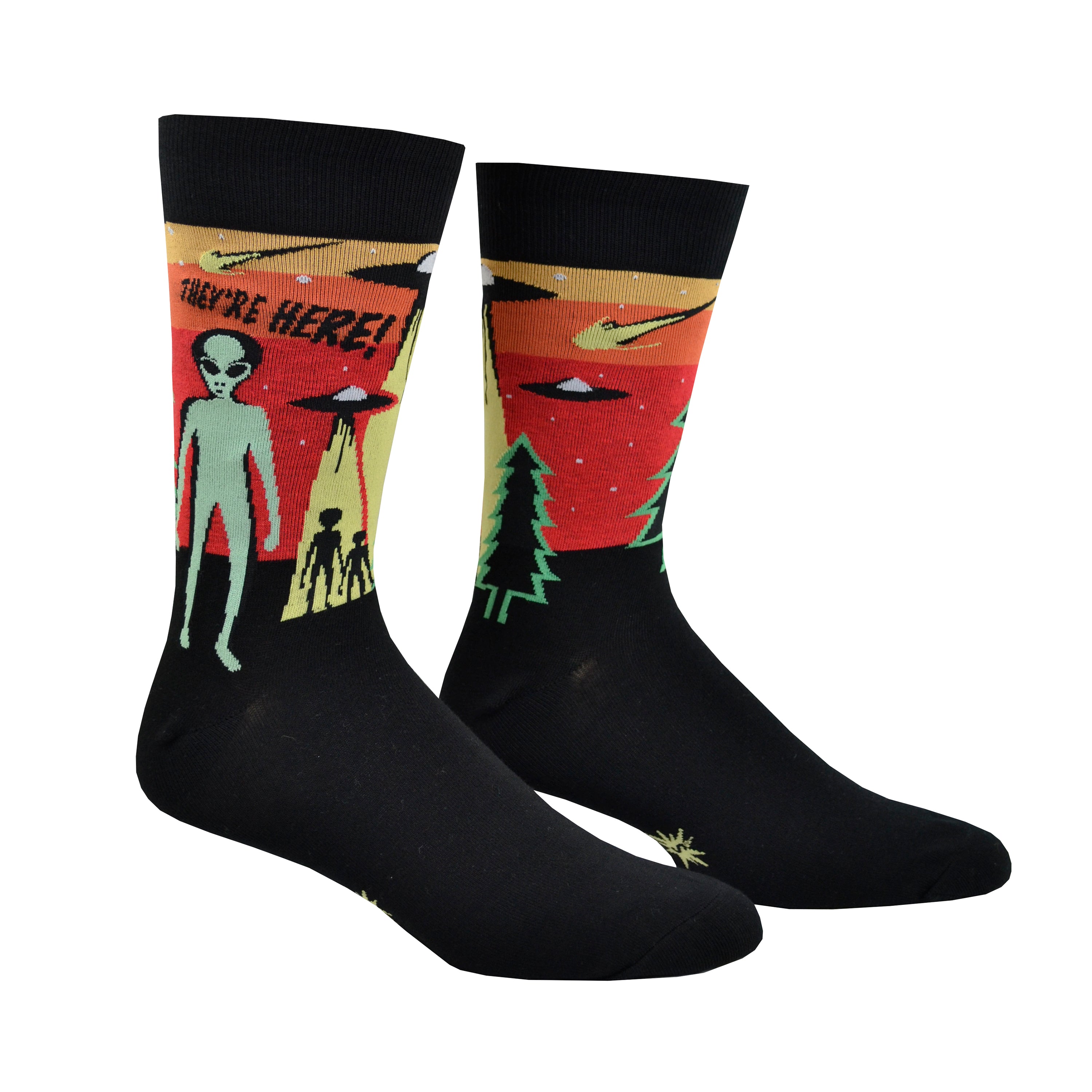 Shown on foot forms, a pair Sock It to Me cotton men's crew socks in black with a yellow, orange, and red background on the leg featuring a green alien and 2 space ships. The text on the sock reads, 