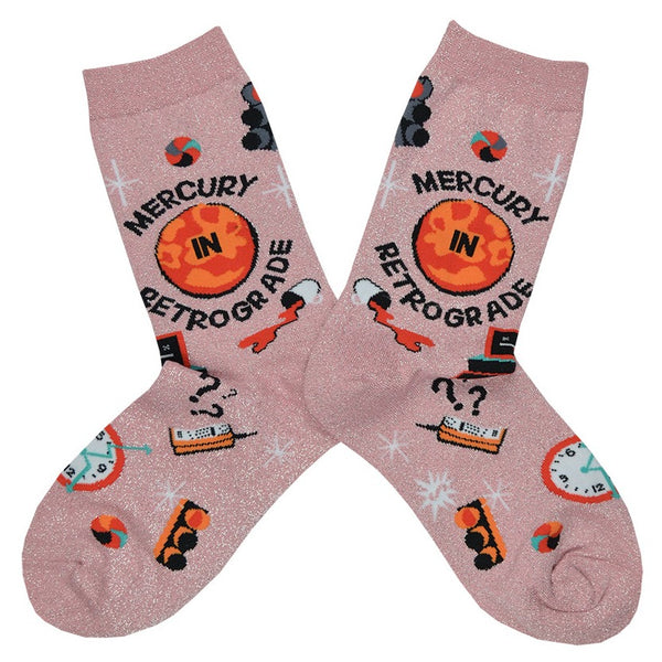 These pink glittery women's crew socks by the brand Sock it To Me feature the words Mercury in Retrograde on the leg with small images of things going wrong throughout, like spilt coffee, a computer crashing and red stop lights.