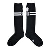Shown in a flatlay, a pair of Sock It To Me brand unisex cotton knee high socks in black with two white stripes around the calf. the back of the sock features a white arrow pointing up to the wearer and says, "BAD ASS".