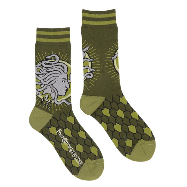 Shown in a flatlay, a pair of unisex dark green socks with a light green heel and toe. The Cuff is striped and the leg of the crew sock has a depiction of Medusa. The foot features a green scale pattern.  