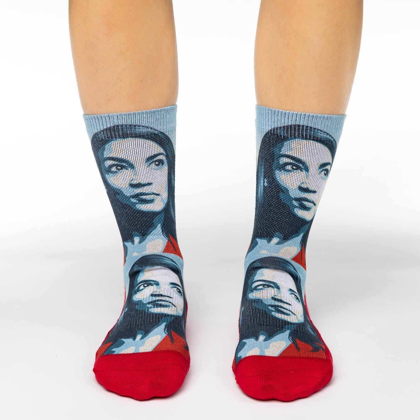 Shown on a foot model, a pair of Good Luck Socks’ polyester-cotton women’s crew socks with portrait of Alexandria Ocasio-Cortez in shades of red, white and blue