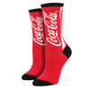 Shown on leg forms, a pair of Sock Smith brand women's cotton crew sock in red with a black heel, toe, and cuff. The leg of the sock features the iconic Coca Cola branding in white lettering.