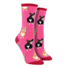 Shown on leg forms, a pair of Sock Smith brand women's cotton crew socks in hot pink with a magenta heel, toe, and cuff. The sock features an all over motif of blonde and black corgi dogs with their little heart shaped butts facing out.