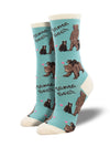 Shown on leg forms, a pair of womens light blue socks with a cream heel, toe and, cuff. They have all over print of brown mother bears and their young with little pink hearts and, cursive script that reads "Mama Bear".