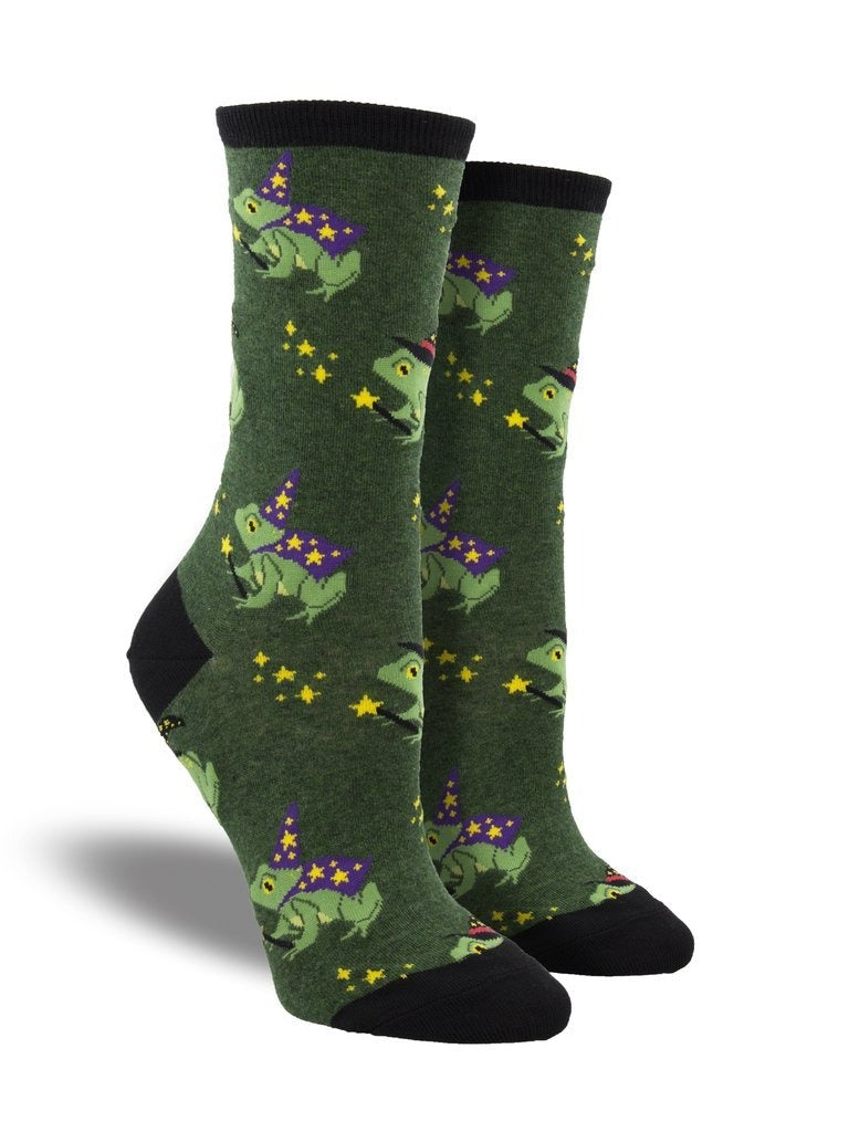 Shown on a leg form, these heather green cotton women's crew socks with a black heel, toe and cuff by the brand Socksmith feature cute green frogs wearing purple wizard outfits and hats, holding a wand with stars coming out of it.