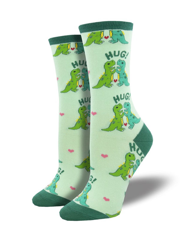These seafoam green women's crew socks with a with a dark green heel, toe and cuff by the brand Socksmith feature adorable dinosaurs hugging with the word HUG! and tiny hearts throughout.