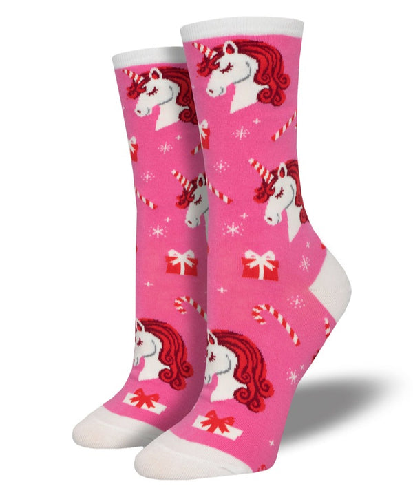 a pair of pink socks on foot forms with a white toe, heel and cuff with a pattern of unicorn faces with horns striped like candy canes, presents and candy