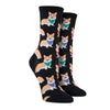 Shown on leg forms, a pair of Sock Smith brand women's cotton crew socks in black featuring an all over motif of blonde corgis in blue, red, and green bandanas.