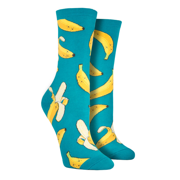 Shown on a leg form, a pair of Socksmith's teal-green cotton women’s crew socks with ripe green banana fruit pattern